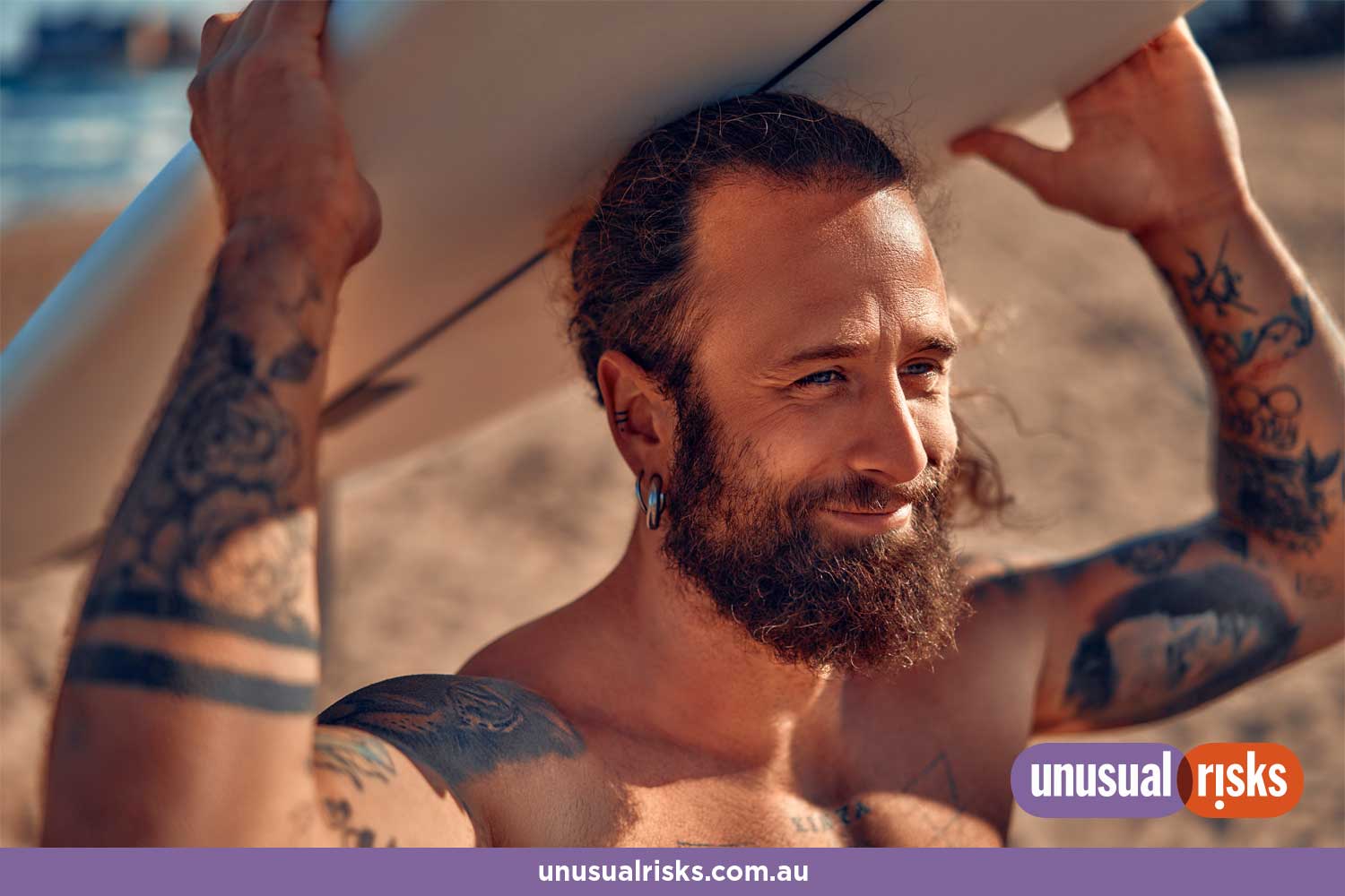 handsome bearded guy at the beach with his favourite surfboard