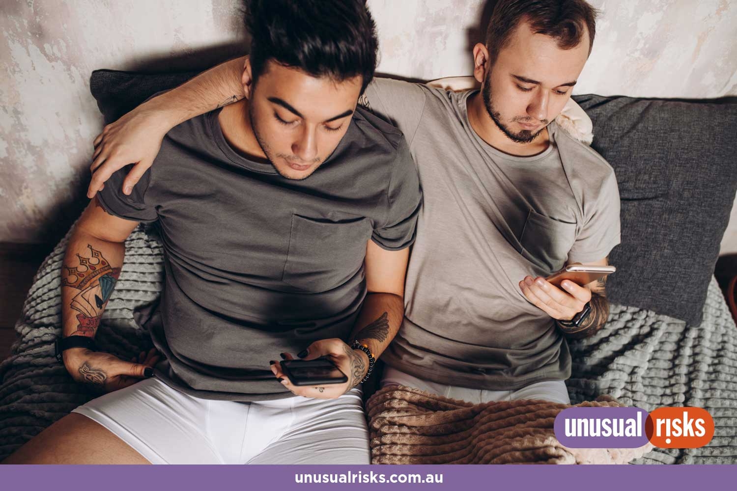 two male partners on their phones sitting close together on a lounge